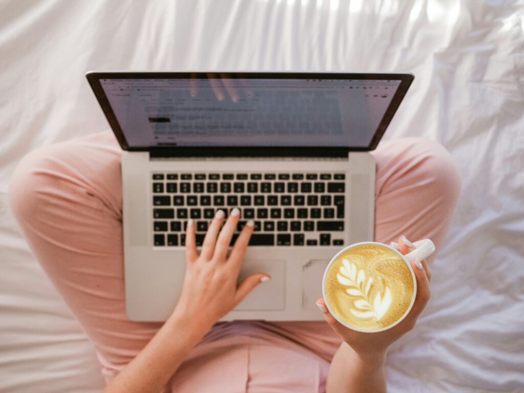 Person using macbook holding cappuccino