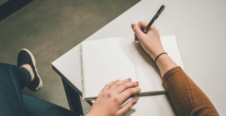 Person writing in a white paper
