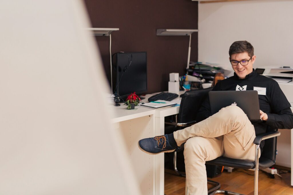 man smiling while are sitting using macbook
